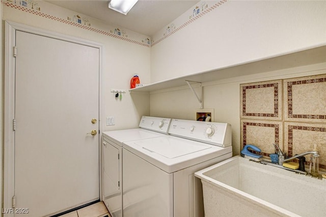 washroom featuring laundry area, light tile patterned floors, washer and clothes dryer, and a sink