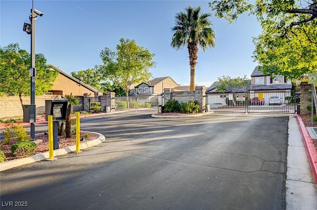 view of road featuring a residential view, a gate, a gated entry, and curbs