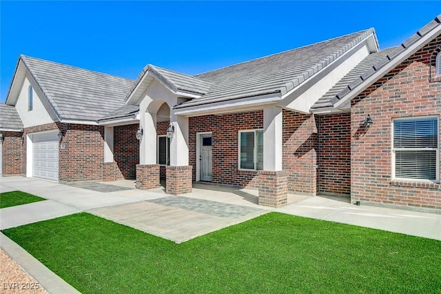 exterior space featuring a yard, brick siding, an attached garage, and a tile roof