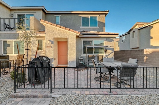 exterior space with a patio, fence, a tiled roof, and stucco siding