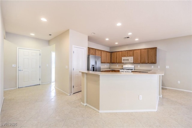 kitchen with white appliances, visible vents, brown cabinetry, light countertops, and recessed lighting