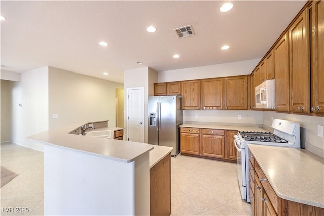 kitchen with white appliances, visible vents, light countertops, and a sink