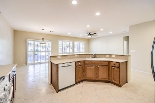 kitchen featuring brown cabinets, light countertops, hanging light fixtures, white dishwasher, and a sink