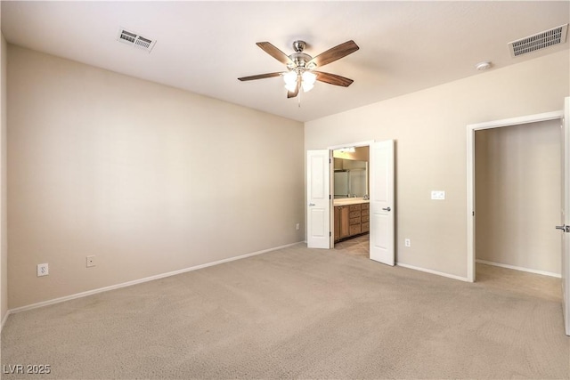 unfurnished bedroom with visible vents, connected bathroom, light carpet, and baseboards