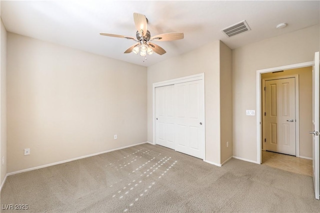 unfurnished bedroom featuring ceiling fan, light carpet, visible vents, baseboards, and a closet