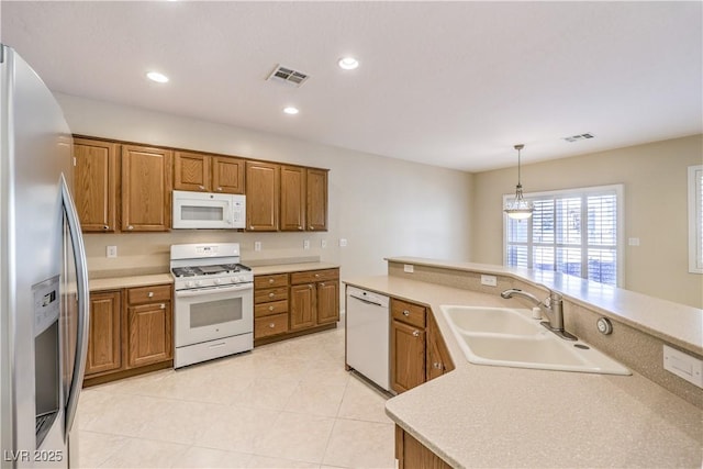 kitchen with white appliances, visible vents, decorative light fixtures, light countertops, and a sink