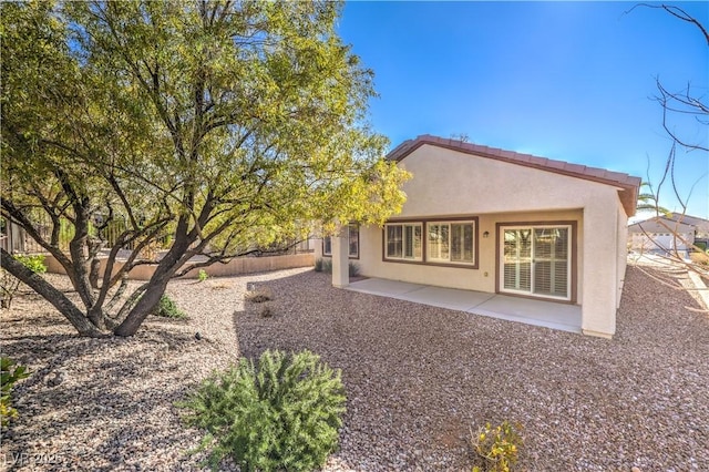 back of property with stucco siding, fence, and a patio