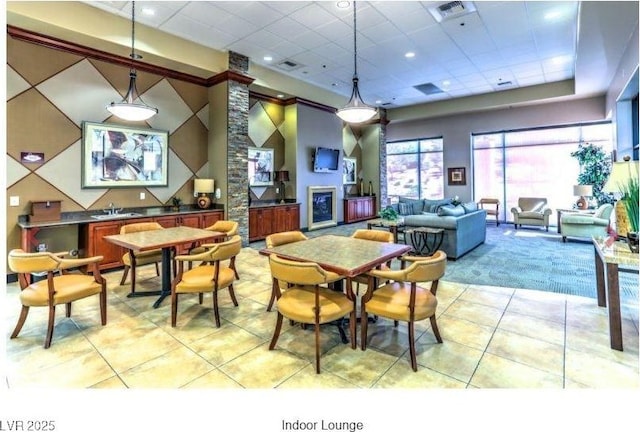 dining area featuring light tile patterned floors, a paneled ceiling, a glass covered fireplace, and visible vents