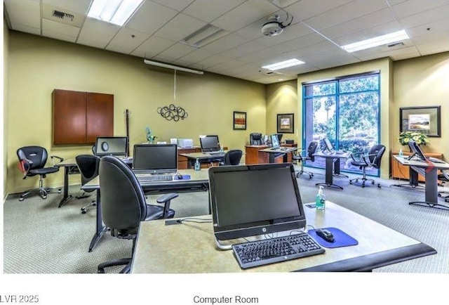 office area with a drop ceiling, visible vents, and a towering ceiling