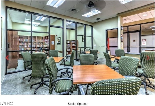 carpeted office space with a paneled ceiling and visible vents