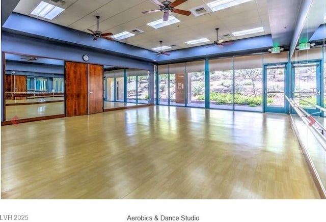 interior space with light wood-style flooring, a wall of windows, a drop ceiling, and a wealth of natural light