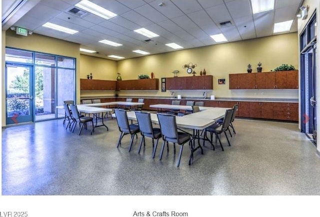 dining space featuring light speckled floor, a drop ceiling, and visible vents