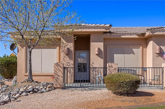 view of exterior entry featuring a gate, a tiled roof, and stucco siding