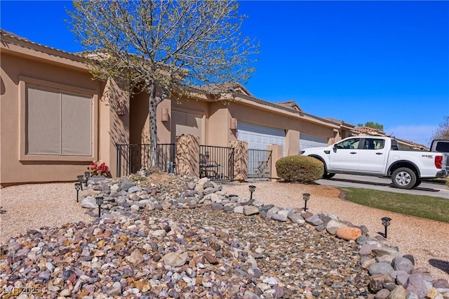 view of front facade with a garage, concrete driveway, fence, and stucco siding