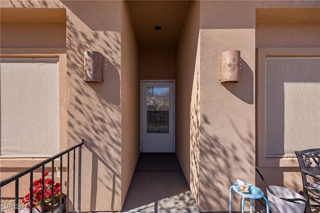 view of exterior entry with a balcony and stucco siding