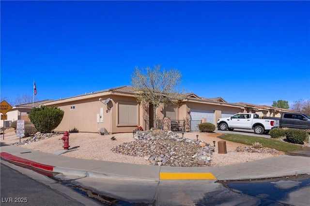 ranch-style home featuring concrete driveway, an attached garage, a tiled roof, and stucco siding