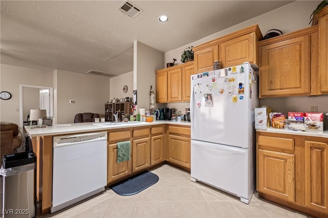 kitchen featuring a peninsula, white appliances, and light countertops