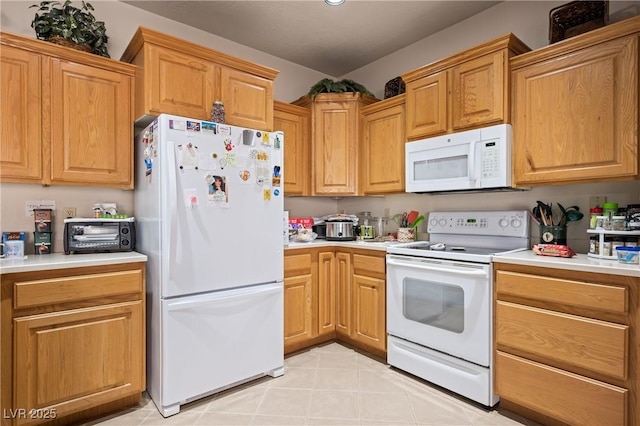 kitchen with light tile patterned floors, a toaster, white appliances, light countertops, and brown cabinetry