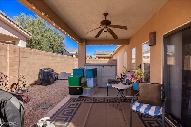 view of patio / terrace with ceiling fan, a shed, and a fenced backyard