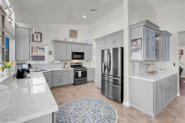 kitchen featuring visible vents, glass insert cabinets, appliances with stainless steel finishes, gray cabinets, and a sink