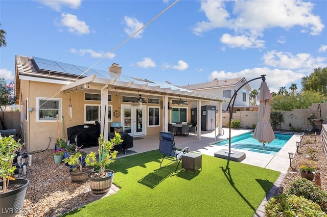 back of house with a fenced backyard, solar panels, french doors, a fenced in pool, and stucco siding