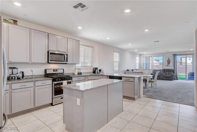 kitchen with a peninsula, visible vents, open floor plan, appliances with stainless steel finishes, and a center island