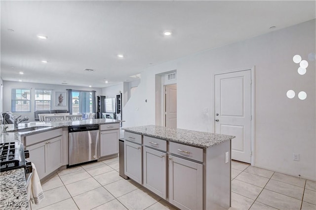 kitchen featuring open floor plan, a kitchen island, a sink, light stone countertops, and dishwasher