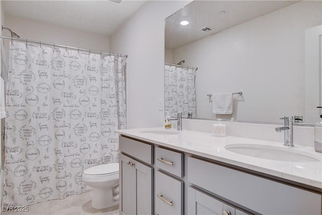 bathroom featuring visible vents, a sink, toilet, and double vanity