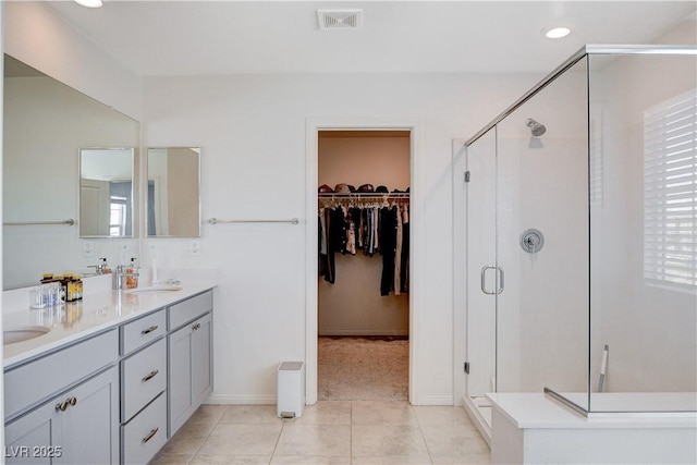 bathroom featuring a sink, visible vents, a spacious closet, tile patterned floors, and a stall shower