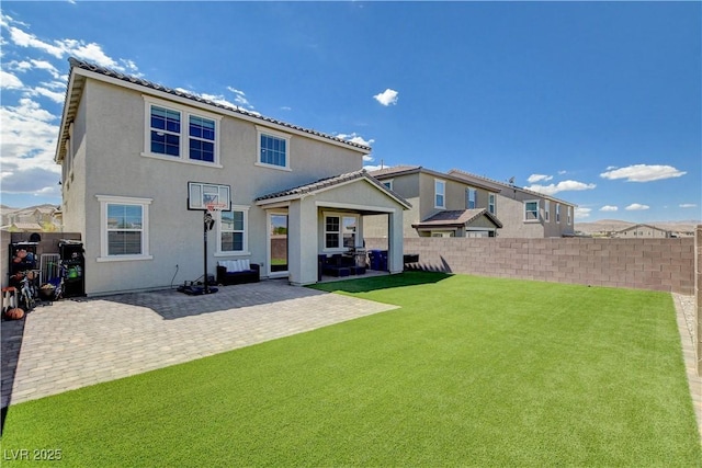 back of house featuring a fenced backyard, a yard, a tiled roof, stucco siding, and a patio area