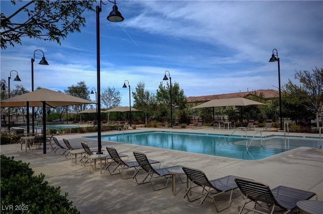 community pool with a patio and fence