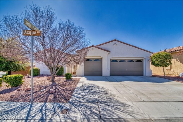 mediterranean / spanish home with a garage, driveway, a tiled roof, and stucco siding