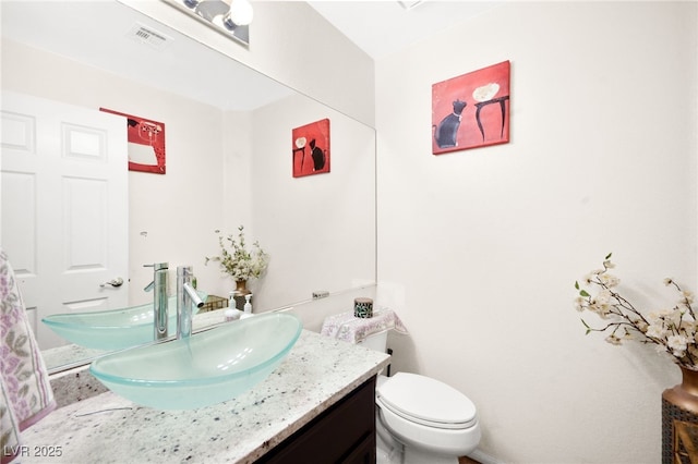 bathroom with toilet, visible vents, and vanity