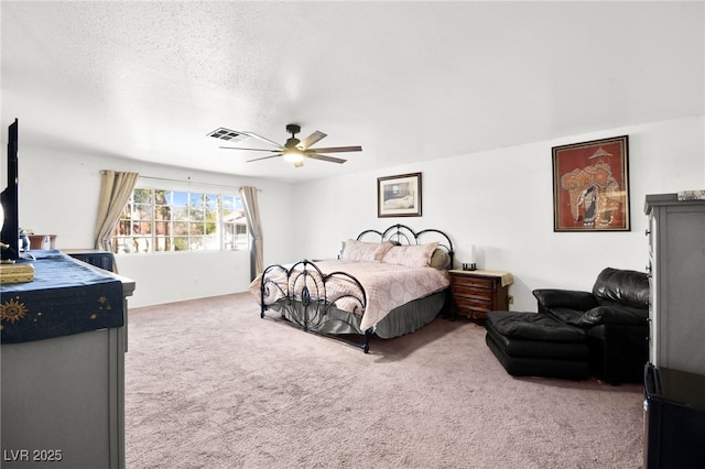 bedroom with carpet floors, visible vents, ceiling fan, and a textured ceiling