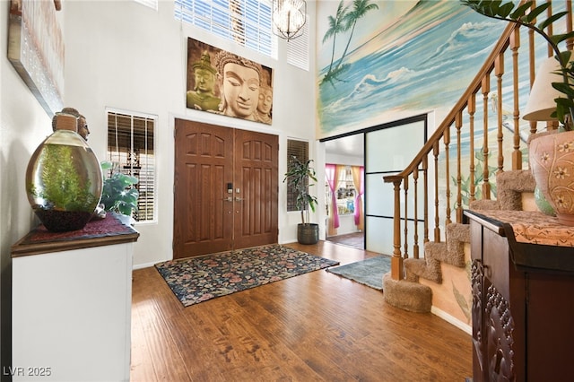 entrance foyer with a chandelier, a high ceiling, stairway, and wood finished floors