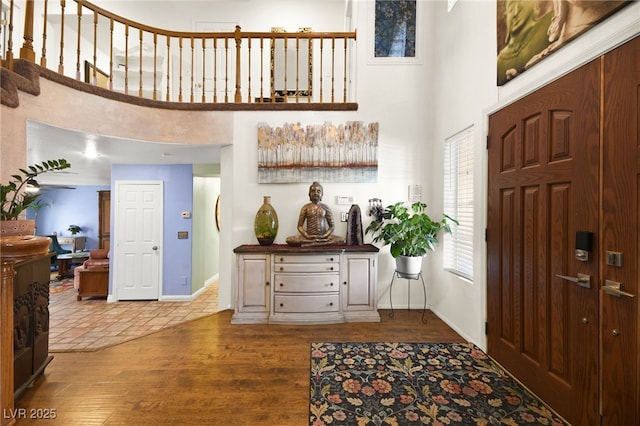 foyer entrance with a towering ceiling, baseboards, and wood finished floors