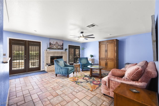 living area featuring ceiling fan, visible vents, french doors, a brick fireplace, and stone finish floor