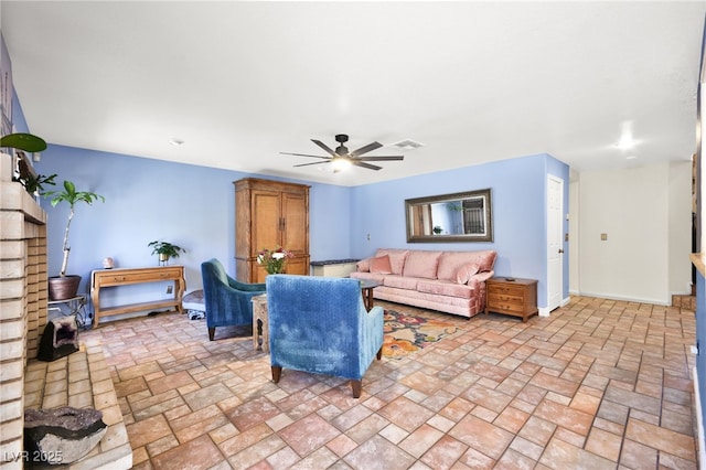 living room featuring baseboards, visible vents, stone finish floor, and ceiling fan