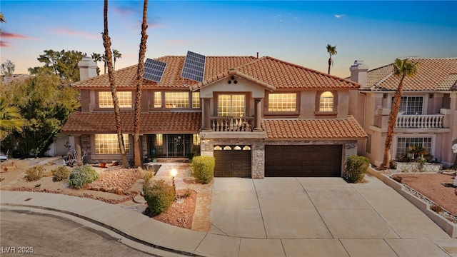 mediterranean / spanish home with a garage, a tile roof, driveway, roof mounted solar panels, and a chimney