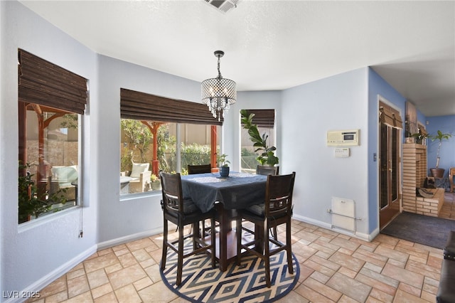 dining space featuring baseboards, a chandelier, visible vents, and stone tile floors