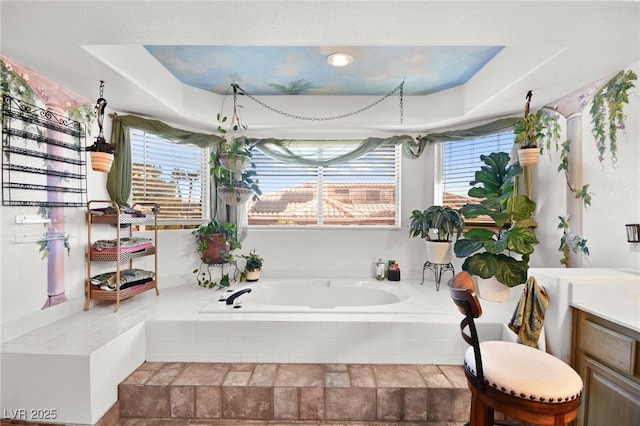 full bathroom featuring a garden tub, plenty of natural light, and a raised ceiling