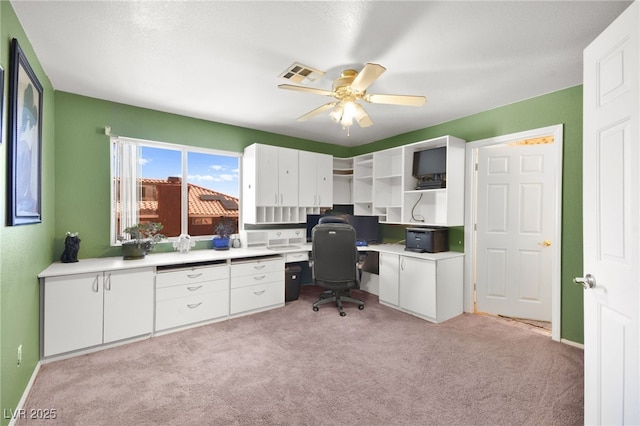 office with baseboards, visible vents, a ceiling fan, and light colored carpet