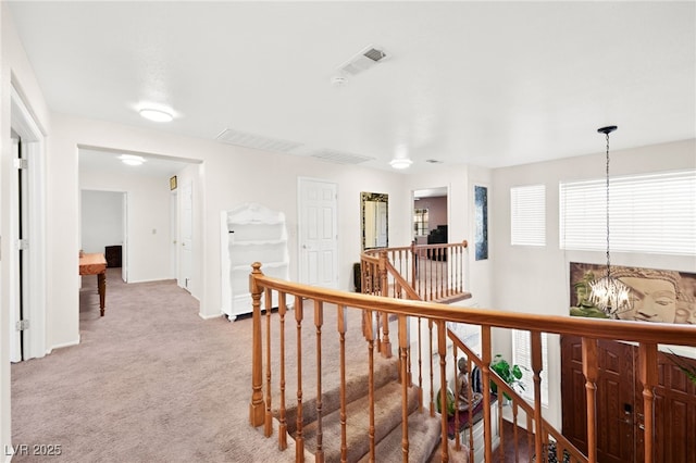 corridor featuring a notable chandelier, visible vents, baseboards, an upstairs landing, and carpet