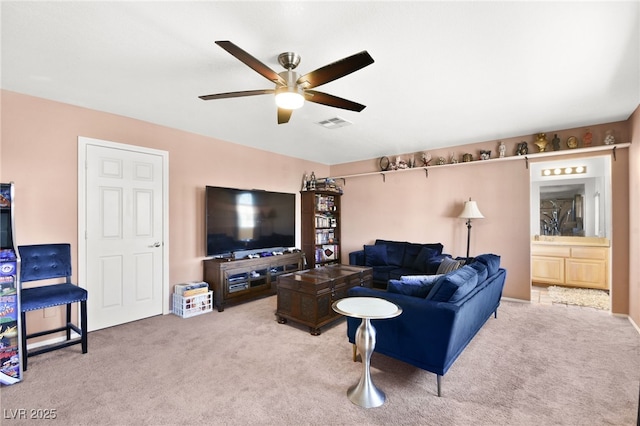 living area with ceiling fan, visible vents, and light colored carpet