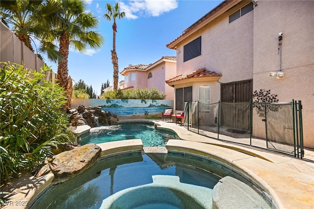 view of swimming pool featuring a pool with connected hot tub and a fenced backyard