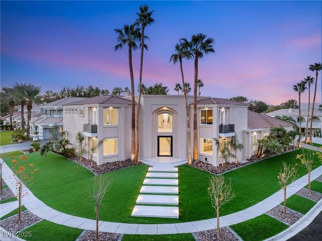 mediterranean / spanish house with a tiled roof, a front lawn, and stucco siding