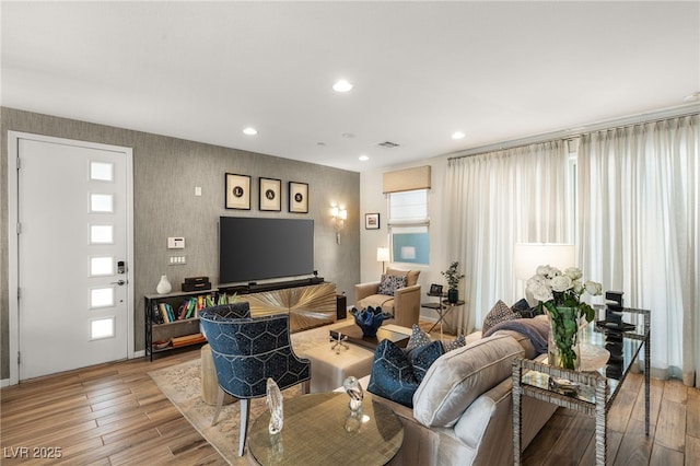 living area with light wood finished floors, visible vents, and recessed lighting