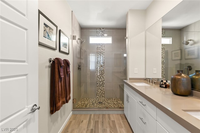 full bathroom featuring a stall shower, wood finish floors, a sink, and double vanity