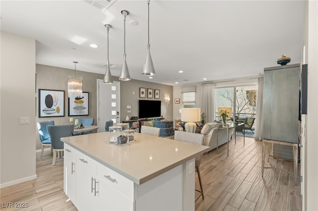 kitchen with open floor plan, a center island, hanging light fixtures, wood tiled floor, and white cabinetry