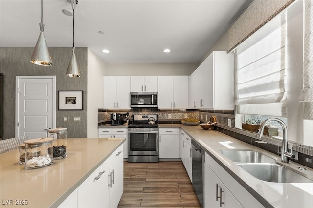 kitchen with pendant lighting, stainless steel appliances, light countertops, and white cabinets